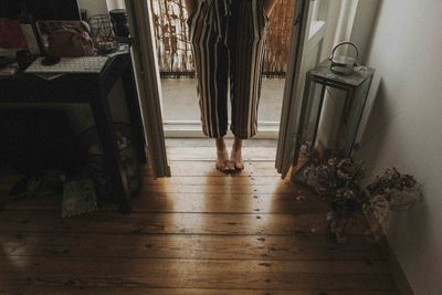 Low section of person standing on hardwood floor at home