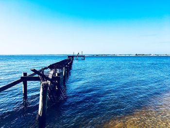 Pier over sea against clear blue sky
