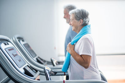 Side view of senior couple exercising at gym