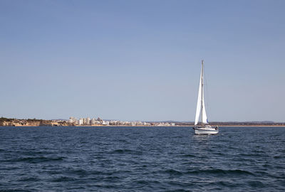 Sailboat sailing on sea against clear sky