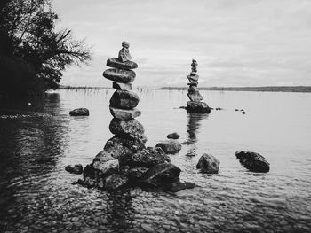 Stack of stones in sea against sky