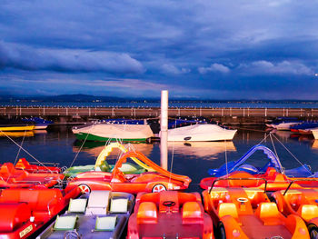 Boats moored at harbor against sky