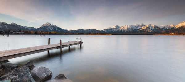 Scenic view of lake by snowcapped mountains against sky