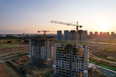 Crane at construction site against sky during sunset