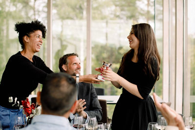 Smiling businesswoman giving trophy to female colleague during kick off meeting at convention center