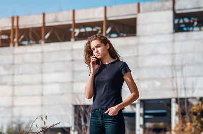 Stylish young woman talking on the phone in industrial district