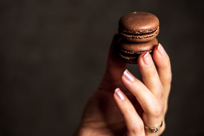 Close-up of hand holding ice cream against black background