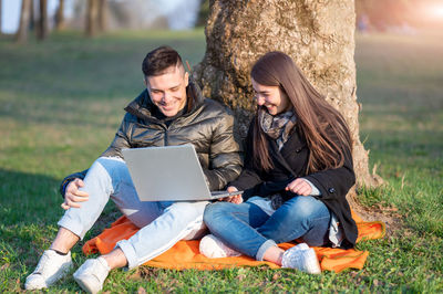 Woman using laptop while sitting on field