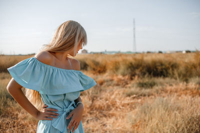 Teenage girl wearing dress standing on land against sky