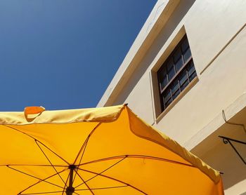 Low angle view of yellow building against blue sky