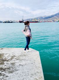 Woman standing by sea against sky