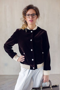 Portrait of young woman standing against wall