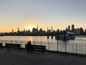 View of river by buildings against sky during sunset