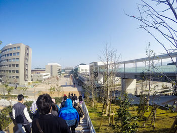 People sitting on bench against clear blue sky