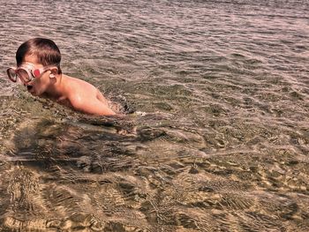 High angle view of shirtless boy swimming in sea