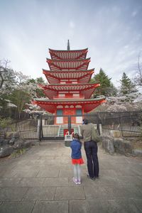 Rear view of people outside temple against building