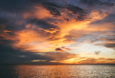 Scenic view of sea against dramatic sky during sunset