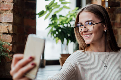 Young woman using mobile phone while sitting on table