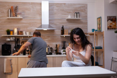 Young woman using mobile phone in kitchen