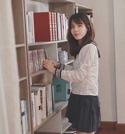 Portrait of young woman standing against wall