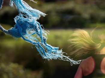 Blue frayed rope blowing in the wind with jogger in the background 
