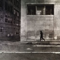 Silhouette woman walking on street against building