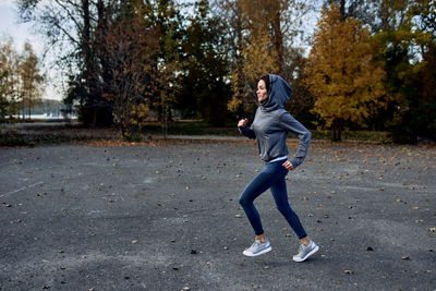 A brunette in a tracksuit runs on the street on the beach.