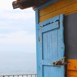 Closed blue door of house against sea