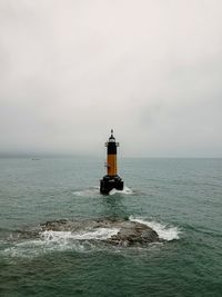 Lighthouse by sea against sky