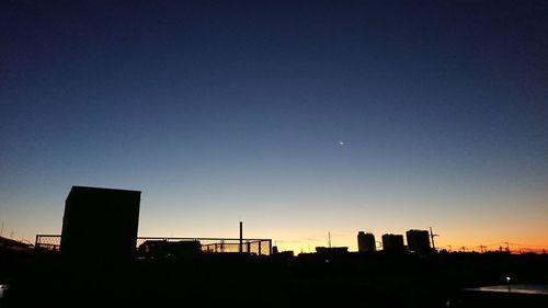 Silhouette buildings against clear sky at sunset