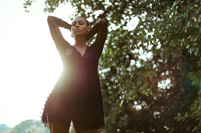 Low angle view of woman with eyes closed standing against clear sky