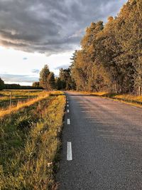 Road amidst field against sky during autumn