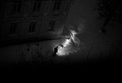 High angle view of silhouette man standing on street in city at night