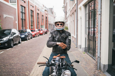 Portrait of man riding motorcycle on street in city