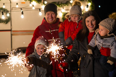 Cheerful family holding sparkler during night outdoors