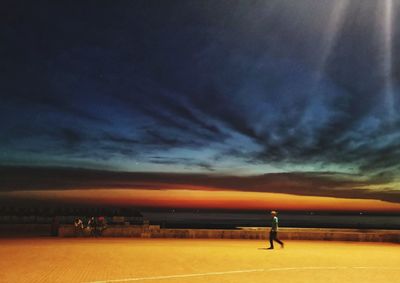 Man standing on land against sky during sunset