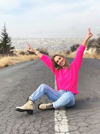 Portrait of young woman sitting on road
