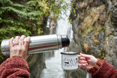 Woman's hand holding a cup of tea. outdoors, cold weather, exploring nature.