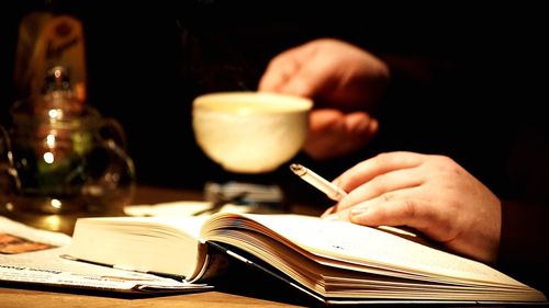 Close-up of hand holding cigarette on book