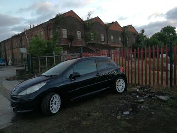 Car on road by buildings against sky