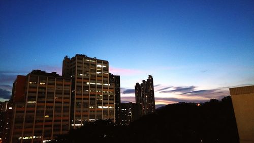 Low angle view of illuminated buildings against blue sky