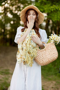 Young woman wearing hat standing against tree