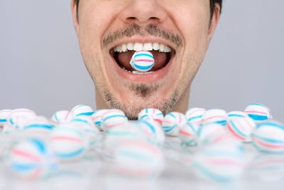 Close-up portrait of young man with candy against colored candy background