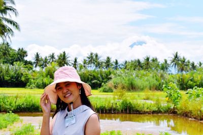 Portrait of young woman standing against lake