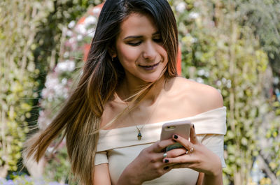 Smiling young woman using smart phone outdoors