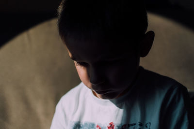 Close-up of shadow falling on sad boy at home