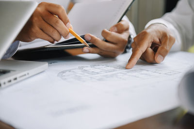 Midsection of businessman working on blueprint