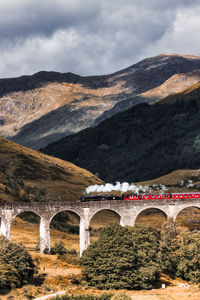 Arch bridge over mountains against sky