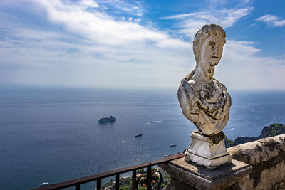 Statue by sea against sky