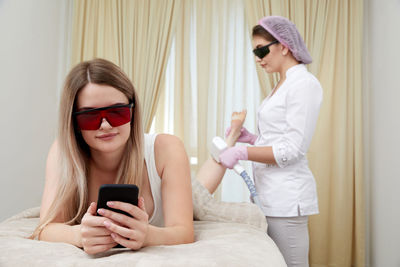 Young woman using mobile phone while sitting at home